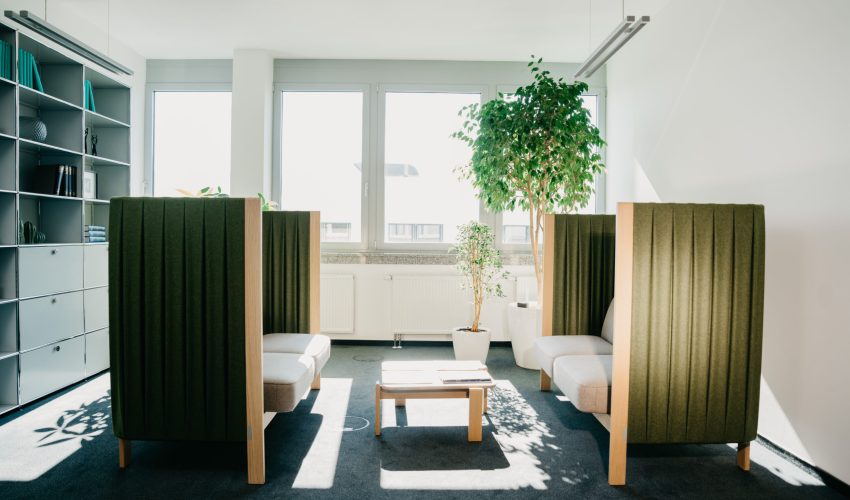 helle sitzecke mit tisch und pflanzen in modernem buero